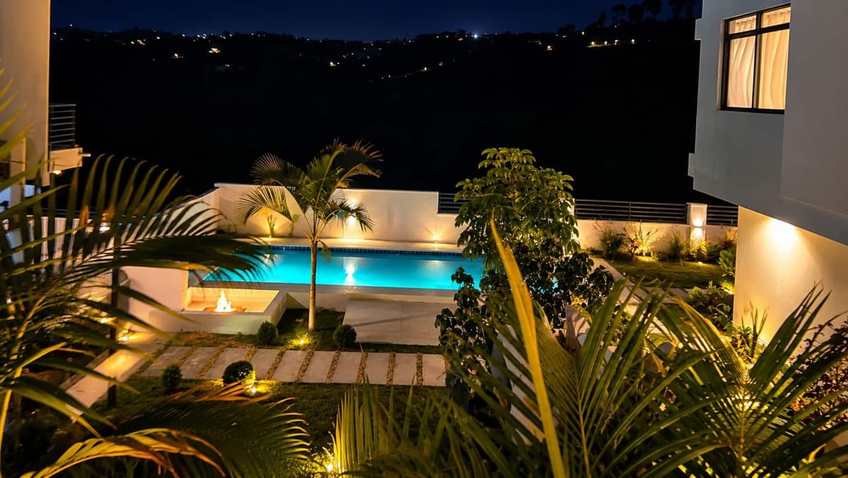 The lit pool and gardens at night, with the hills dark beyond. Amahoro, Kibagabaga.