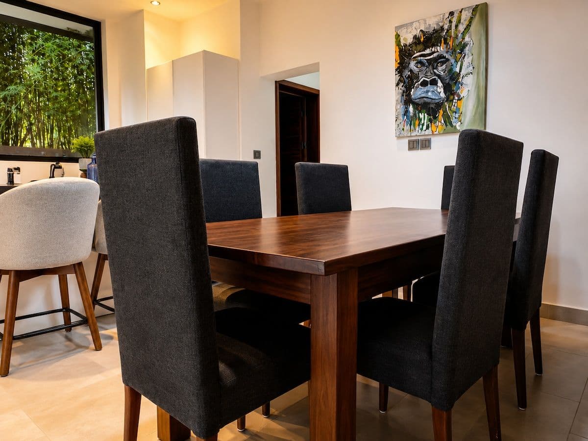 The open-plan dining area, with a wooden table and a painted gorilla on the wall. Ikaze, Kicukiro.