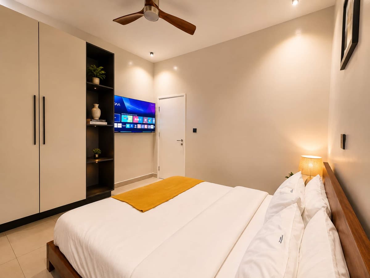 A bedroom with a large bed, a mustard throw and a wall-mounted TV. Amahoro, Kibagabaga.