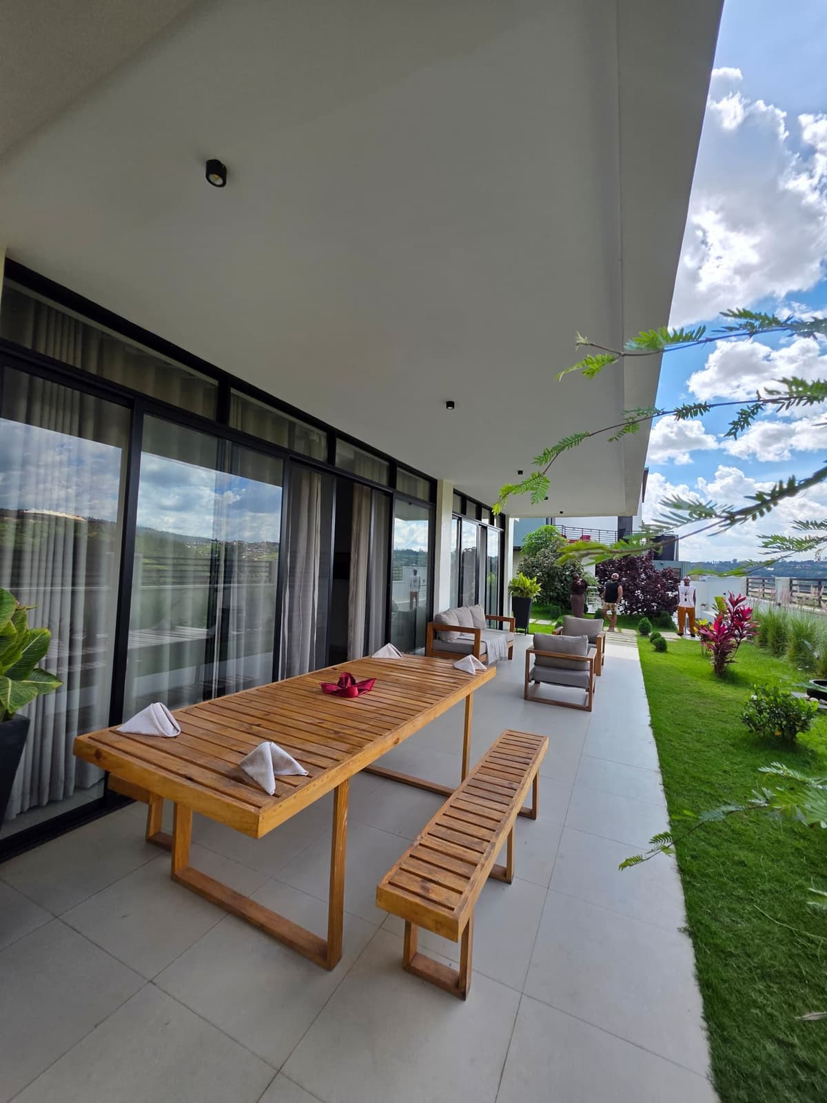 A long timber table for dining outdoors, beside the glass-walled villa. Amahoro, Kibagabaga.