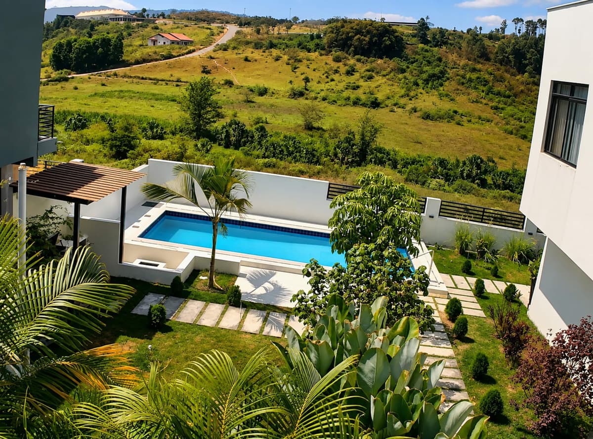 The pool seen from above, set in the garden with green hills beyond. Amahoro, Kibagabaga.