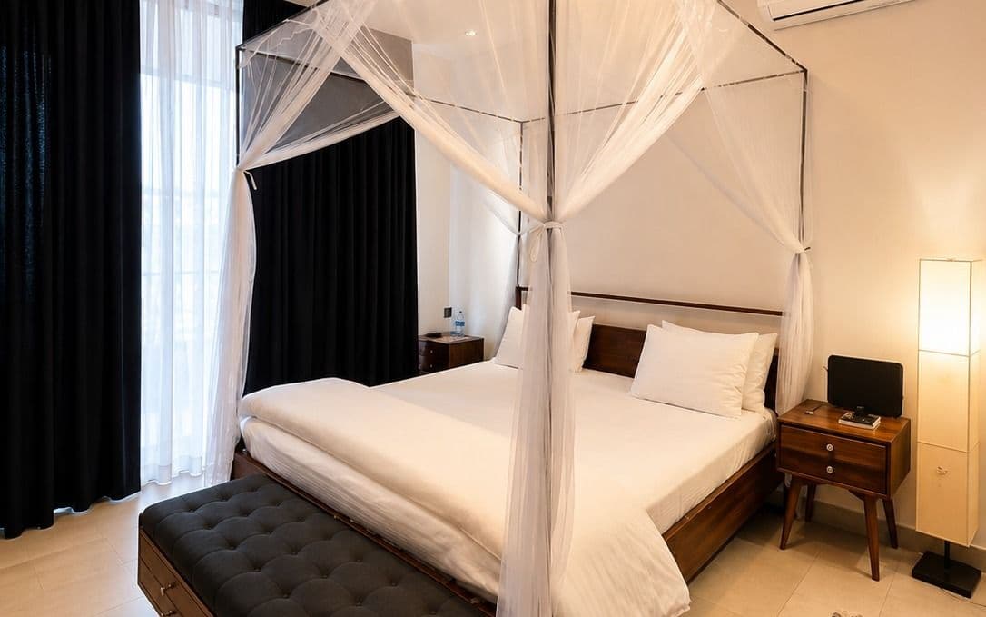 The principal suite at Ikaze, a king bed under a canopy in warm light, Niboye, Kigali
