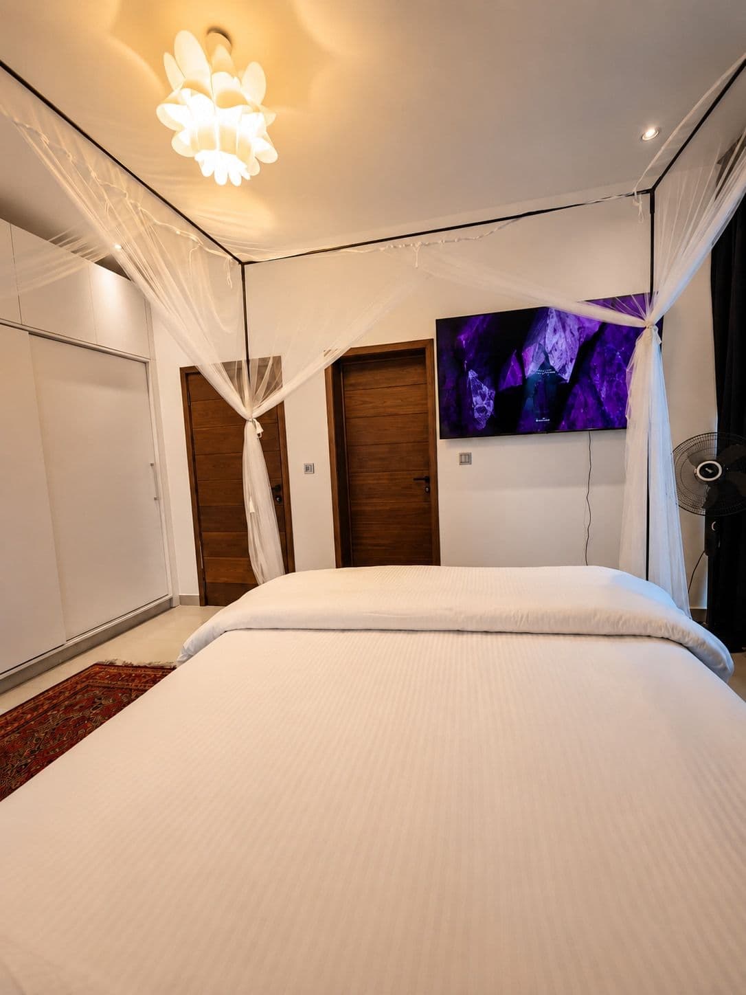 A canopy bed with a wall-mounted TV and fitted wardrobes. Ikaze, Kicukiro.