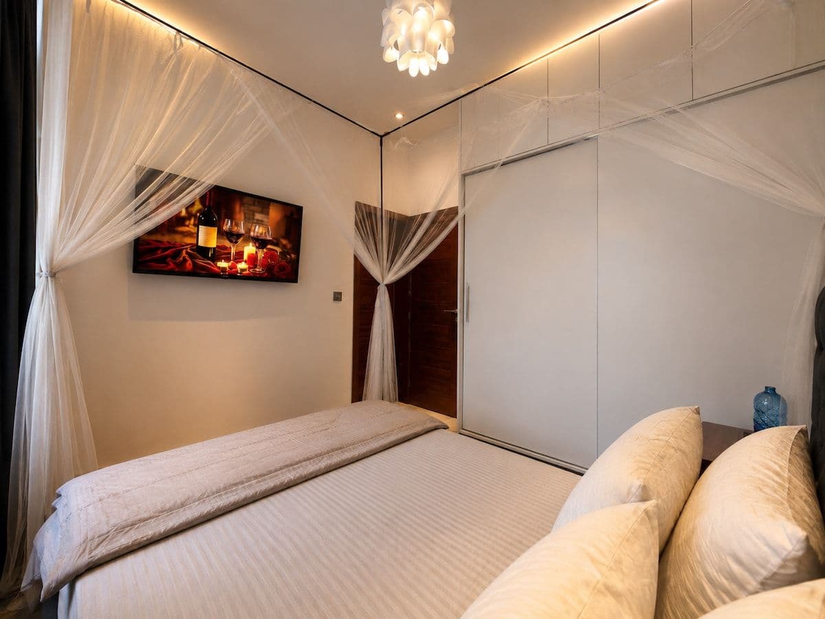 A second bedroom, with a bed under a net and a wall TV. Ikaze, Kicukiro.