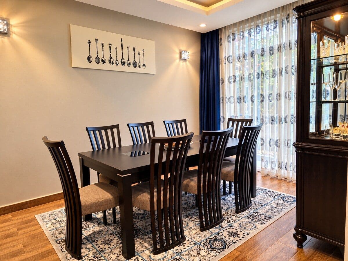 A dining table for six on a patterned rug, beneath framed wall art. Irebero, Rebero.