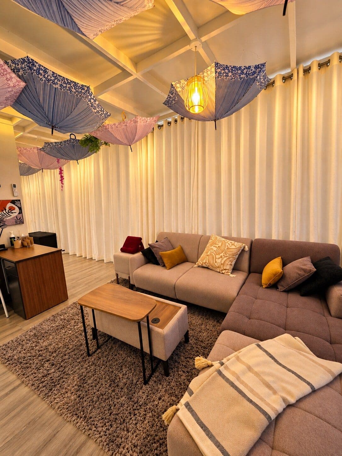 A sofa beneath the umbrella canopy, with curtains and soft lamps. Irebero, Rebero.