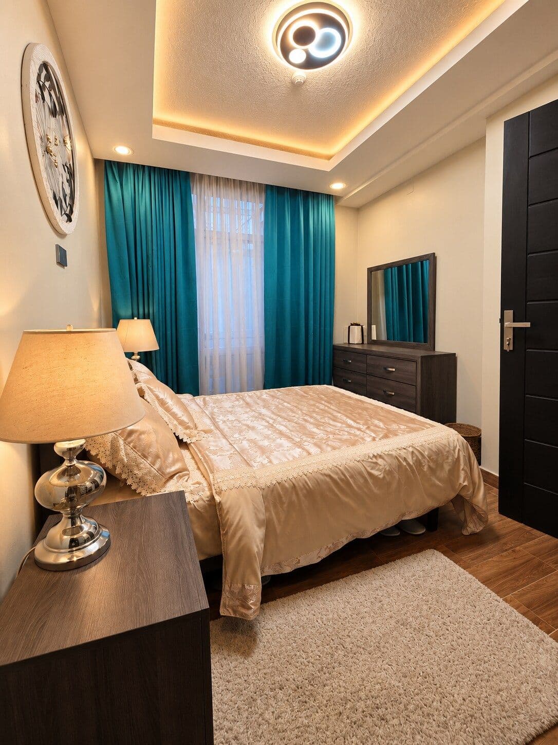 A brass bedside lamp beside the gold bedding. Irebero, Rebero.