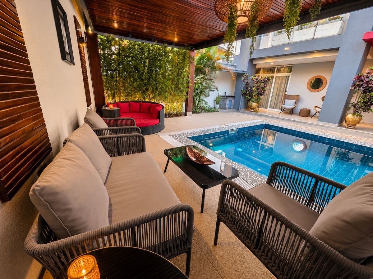 A covered lounge beside the pool at Irebero, with lamps lit and a red daybed, Rebero, Kigali