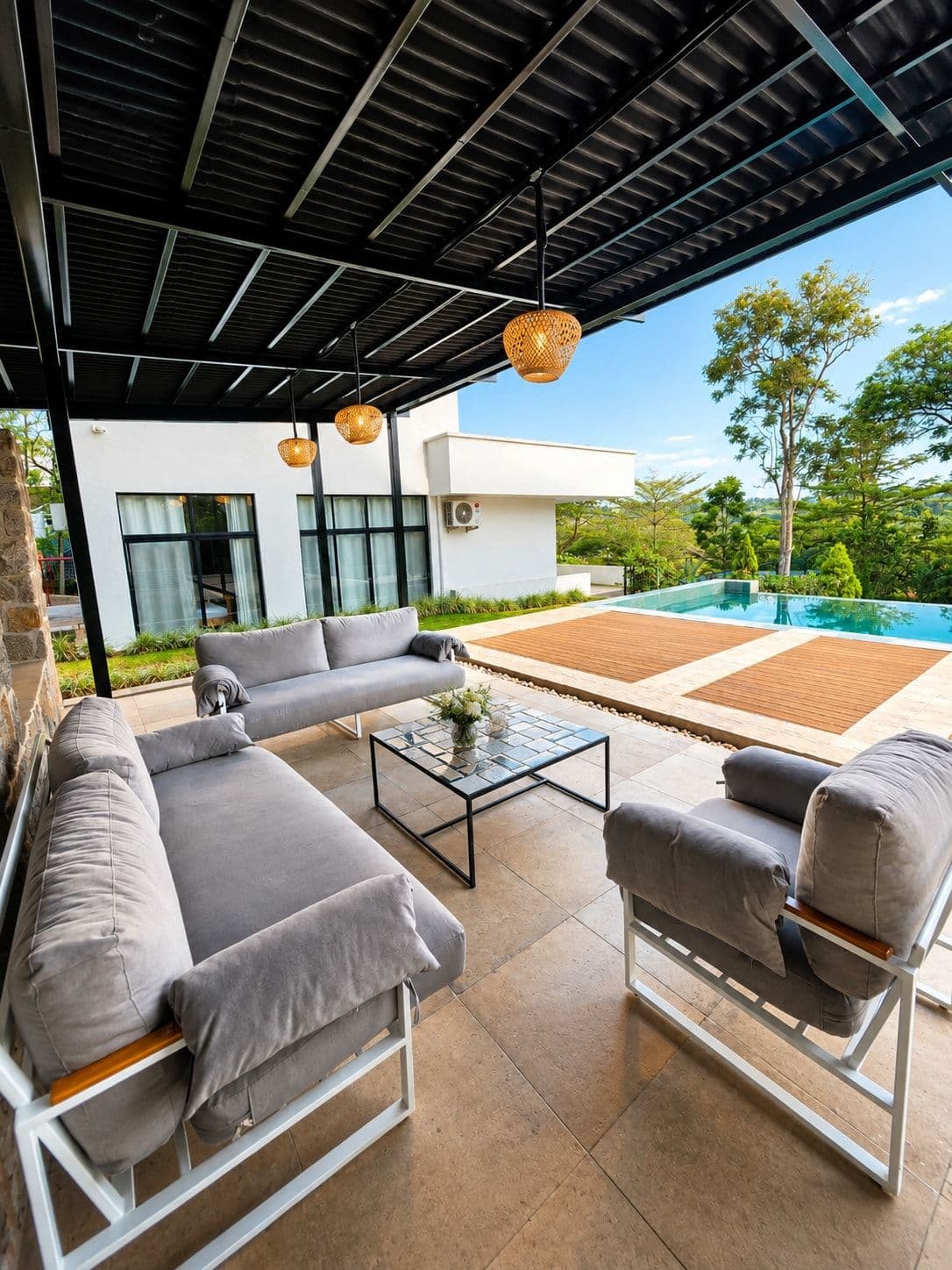 A covered outdoor lounge with grey sofas, above the pool. Urugwiro, Kacyiru.