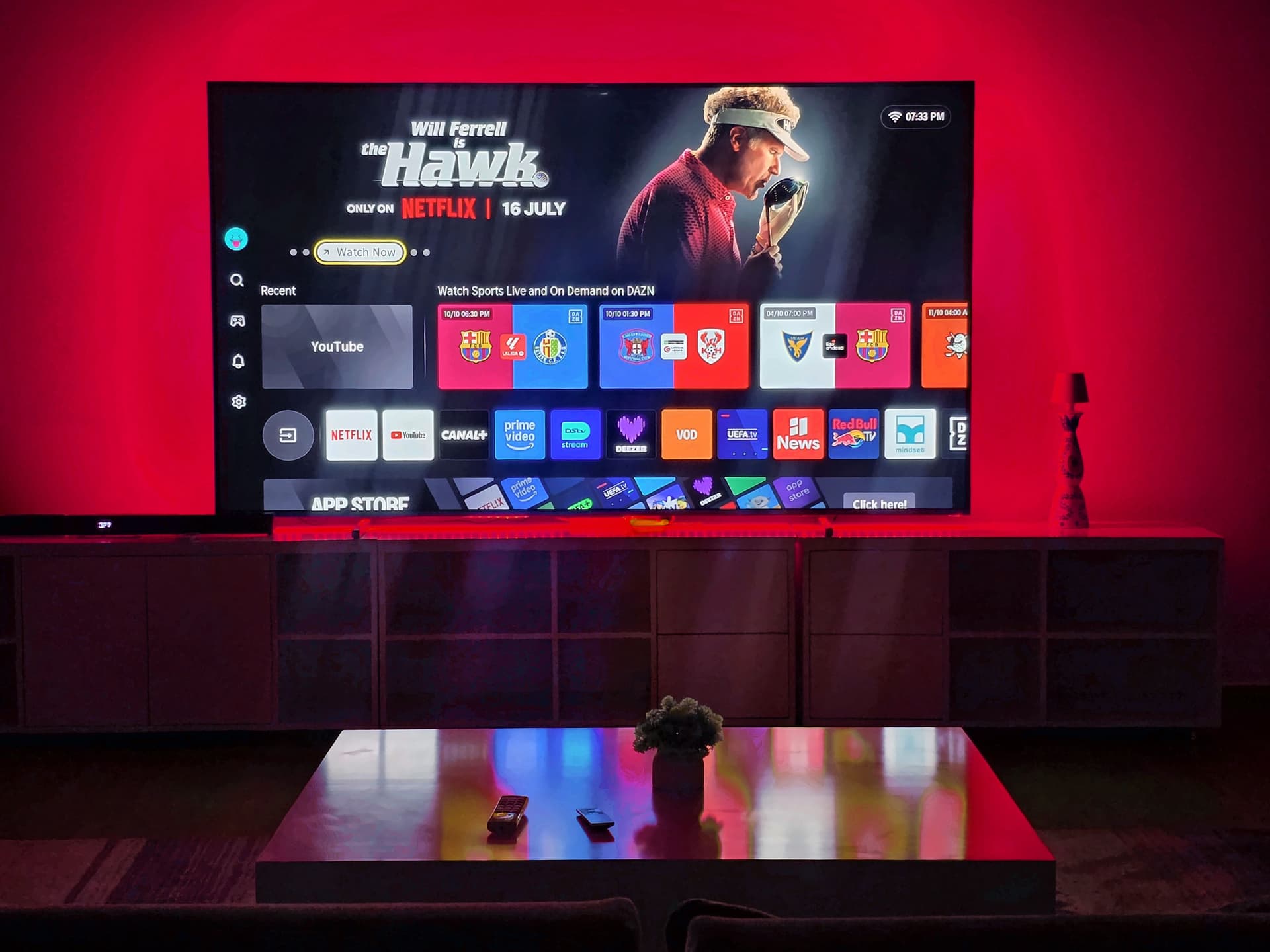 The living room at night as a private cinema, a 100-inch screen glowing in red light. Urugwiro, Kacyiru.